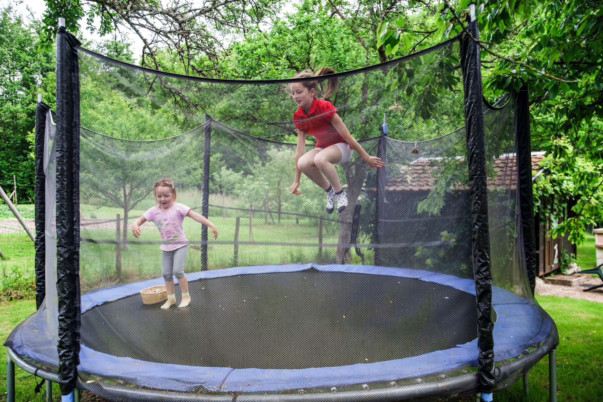 Tips For Homeowners To Avoid Trampoline Injury Liability - Two happy sisters on trampoline